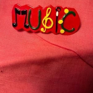 Red barrette hair clip “music” written on it